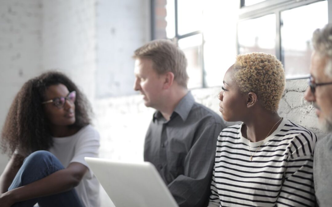 Groep diverse collega's bekijkt samen een online aanbieding op een laptop