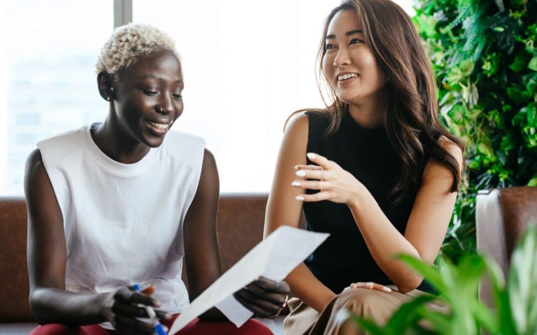 Twee diverse collega's bekijken samen een document met algemene voorwaarden op kantoor