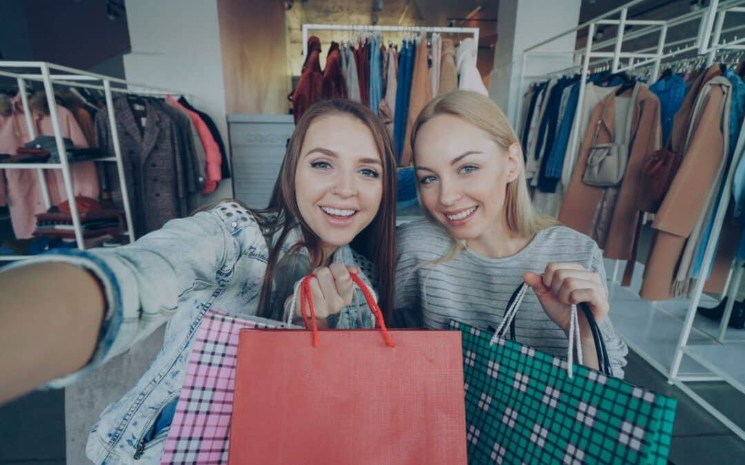 Twee vrouwen met boodschappentassen kijken naar korting in een kledingwinkel