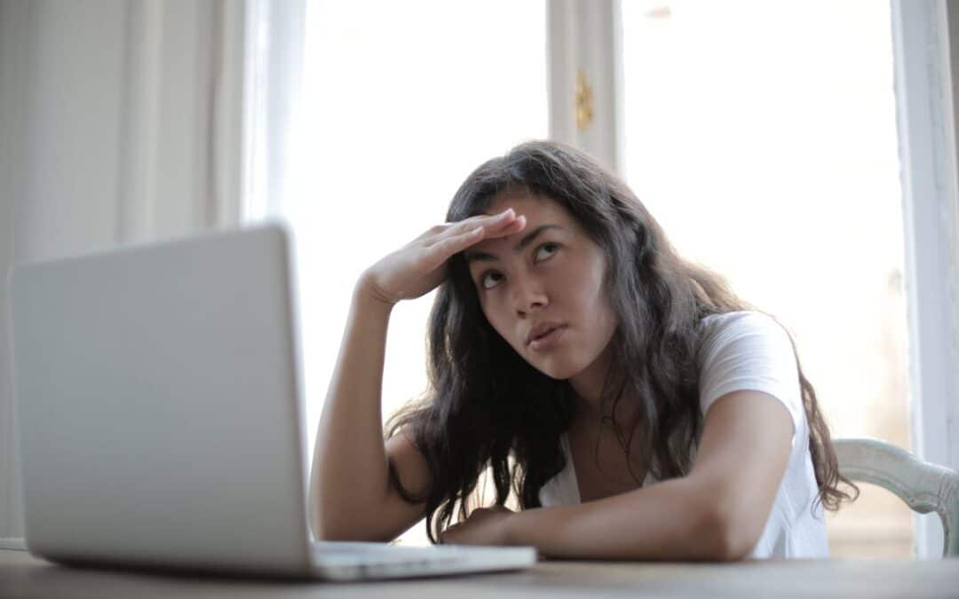 Vrouw kijkt bezorgd op terwijl ze achter haar laptop een online bestelling controleert