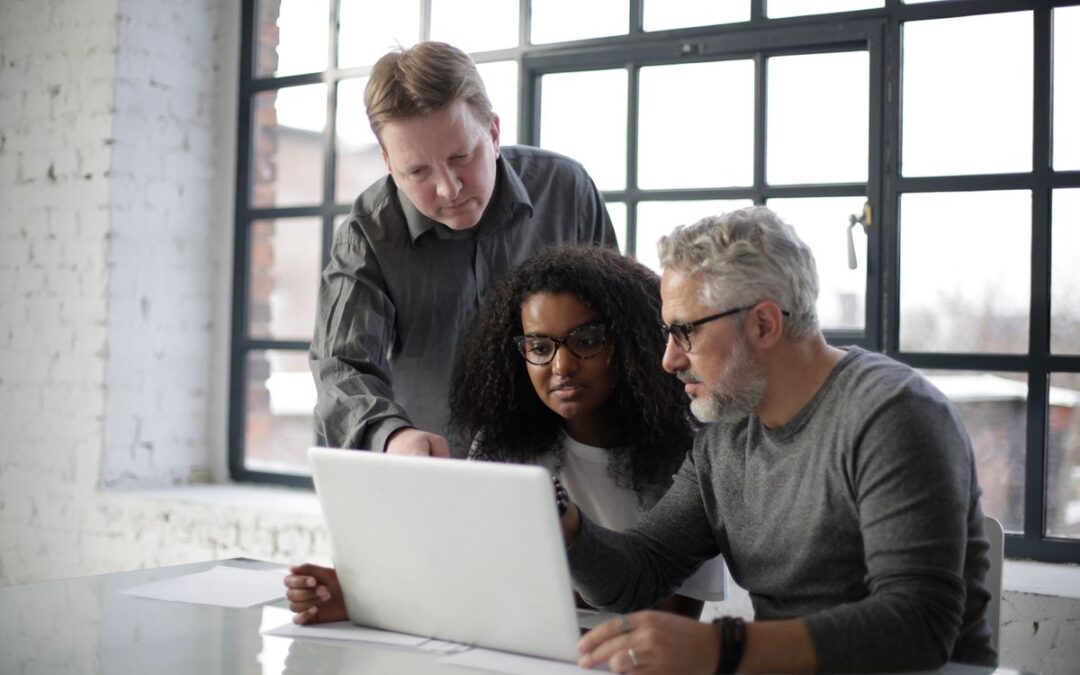 Collega's overleggen samen aan een laptop over digitale beveiliging op de werkvloer