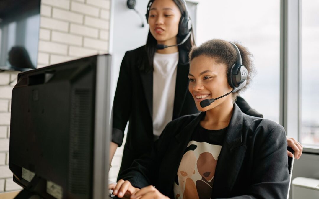 Twee medewerkers van de klantenservice beantwoorden vragen via telefoon en chat op kantoor