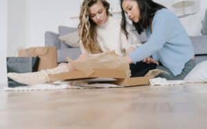 Twee vrouwen pakken samen enthousiast een online bestelde pakketdoos uit