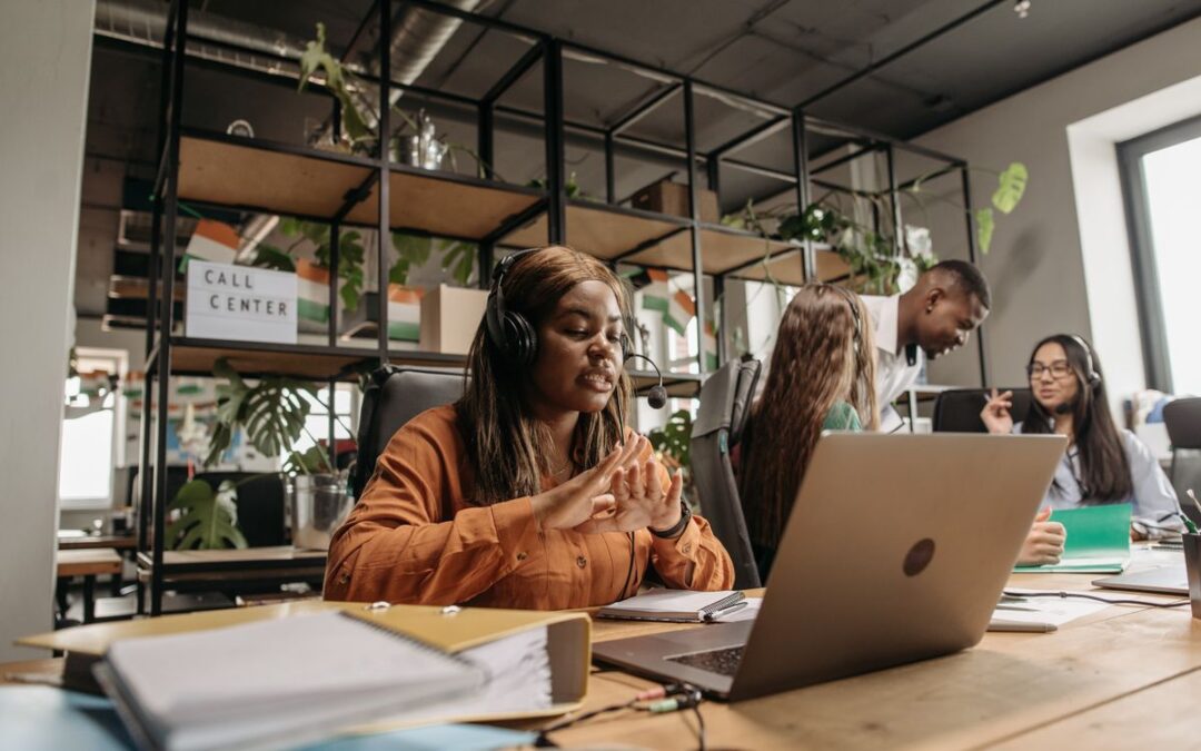 Divers team van klantenservicemedewerkers met headset achter laptops in een modern kantoor