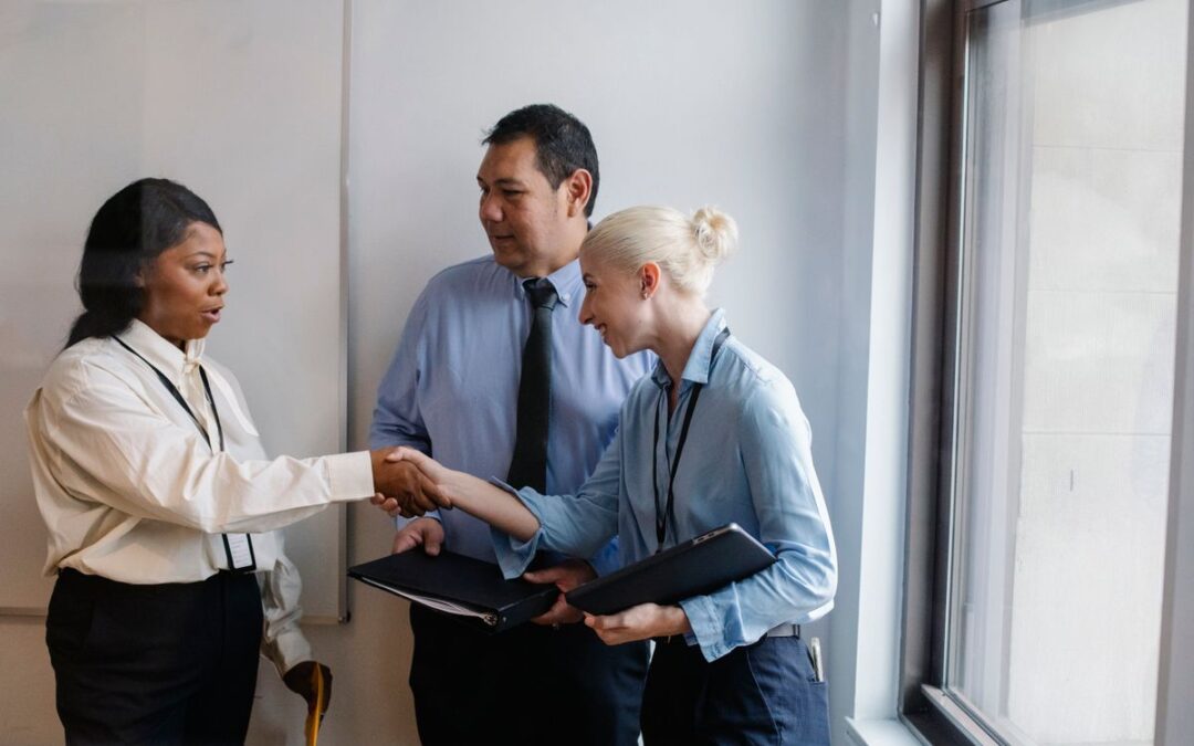 Twee zakenpartners in diverse samenstelling schudden elkaar de hand na een overleg op kantoor