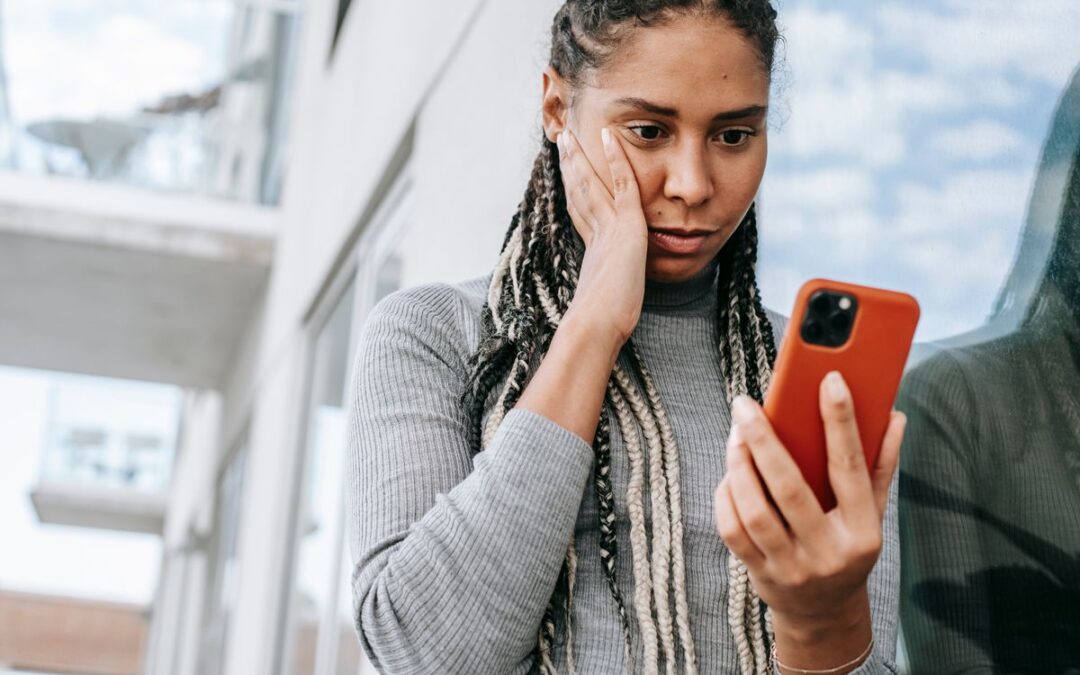 Vrouw kijkt bezorgd naar een verdacht bericht op haar telefoon, mogelijk phishing