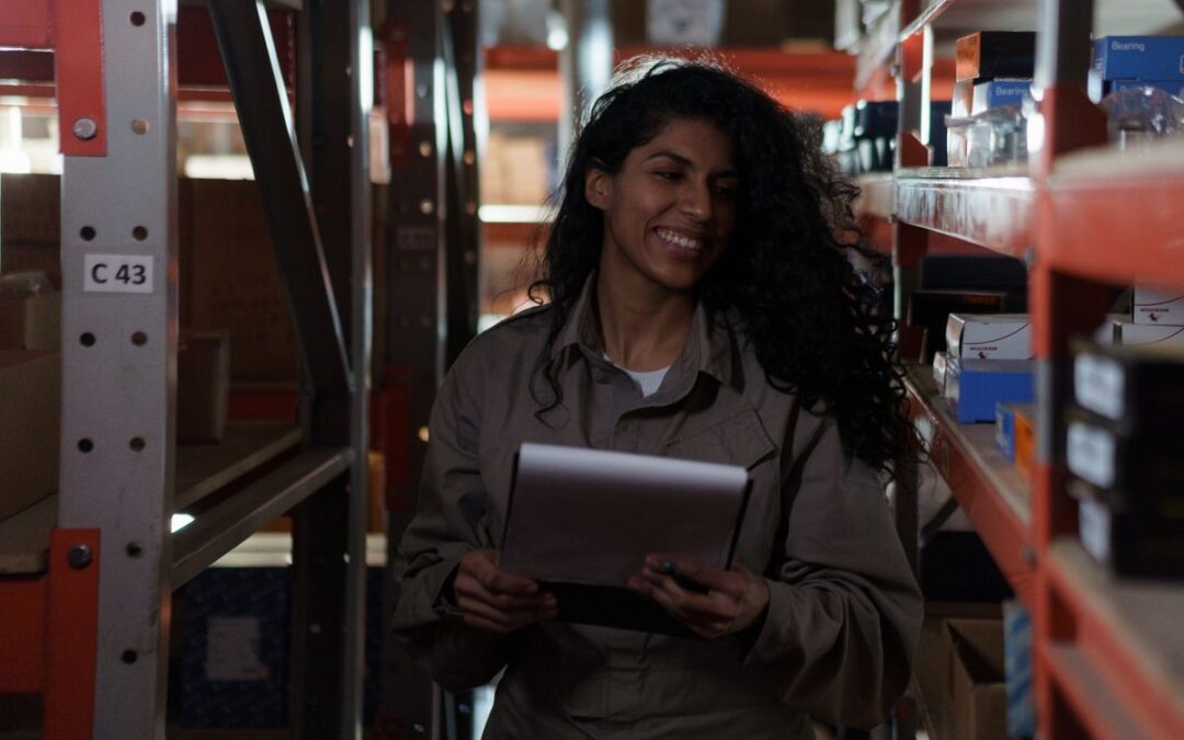 Vrouw controleert de voorraad in een magazijnstelling met een tablet in de hand