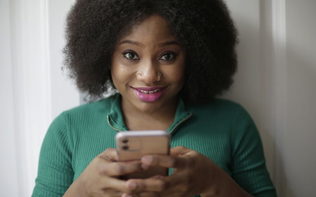 Vrouw kijkt lachend naar haar smartphone tijdens WhatsApp-klantcontact met een webshop