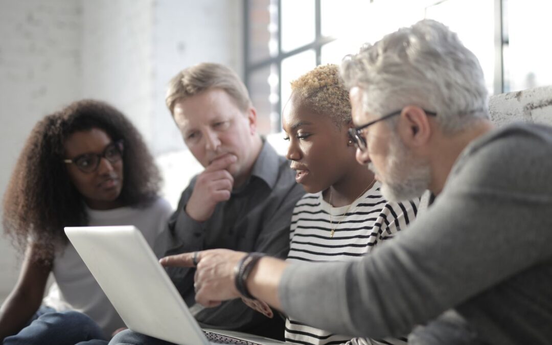 Divers team bekijkt samen productinformatie op een laptop scherm