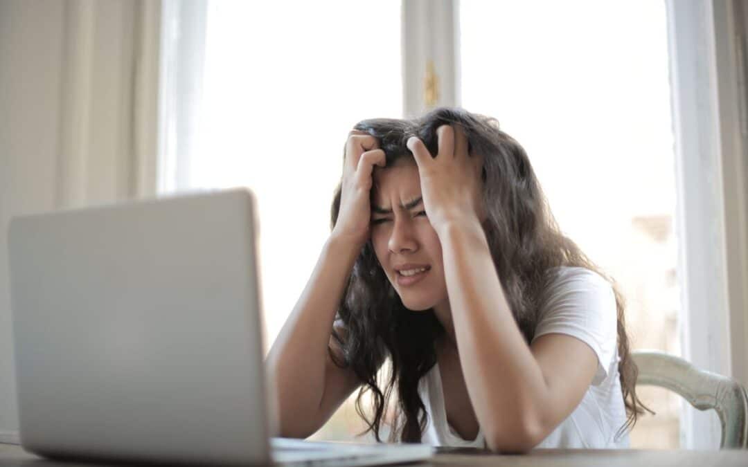 Gestreste vrouw kijkt naar laptop na online betaalfraude
