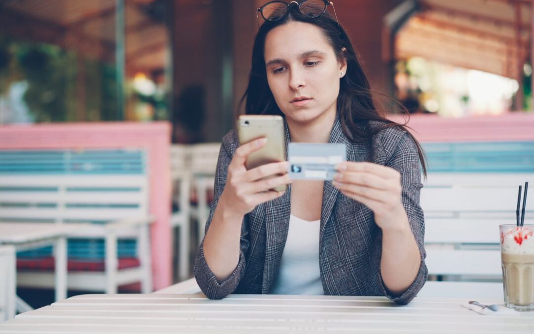 Vrouw betaalt online met smartphone en betaalkaart op een terras