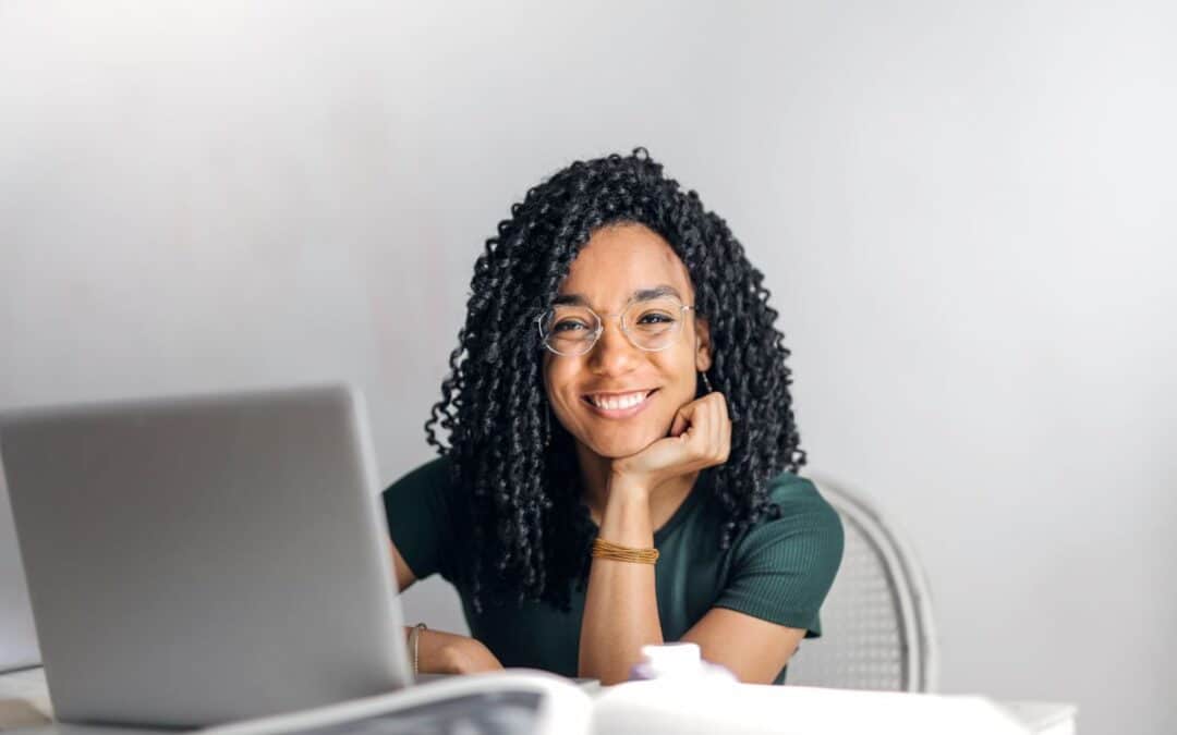 Lachende webwinkelier aan een laptop, klaar om de laadsnelheid van de webshop te testen