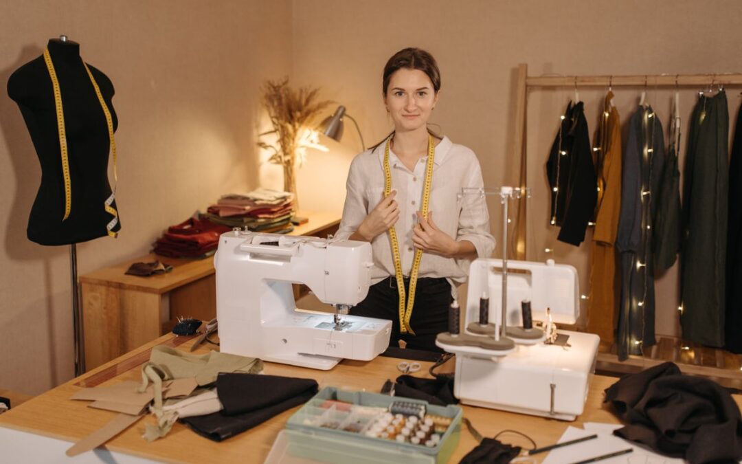 Kledingmaakster met meetlint om haar nek in een atelier met naaimachines en kleding aan een rek