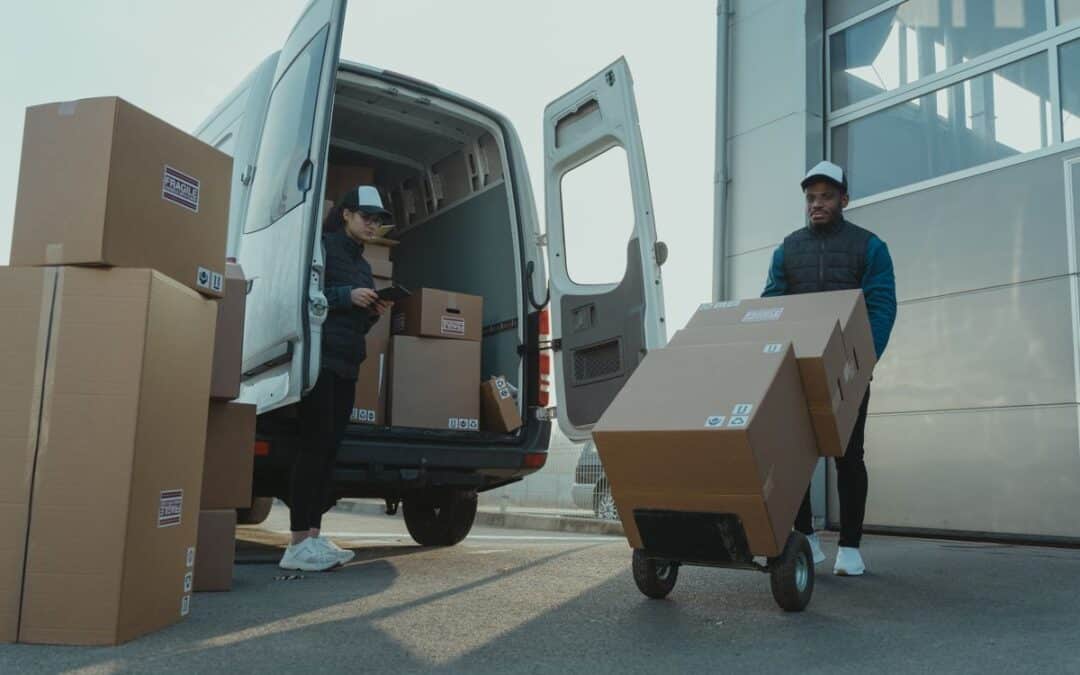 Twee bezorgers laden en vervoeren verpakte pakketten bij een bestelbus