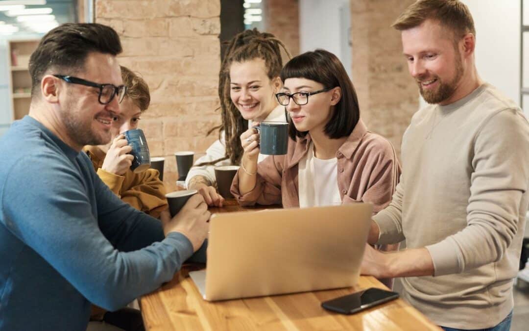 Divers team van webshopmedewerkers bekijkt samen productgegevens op een laptop